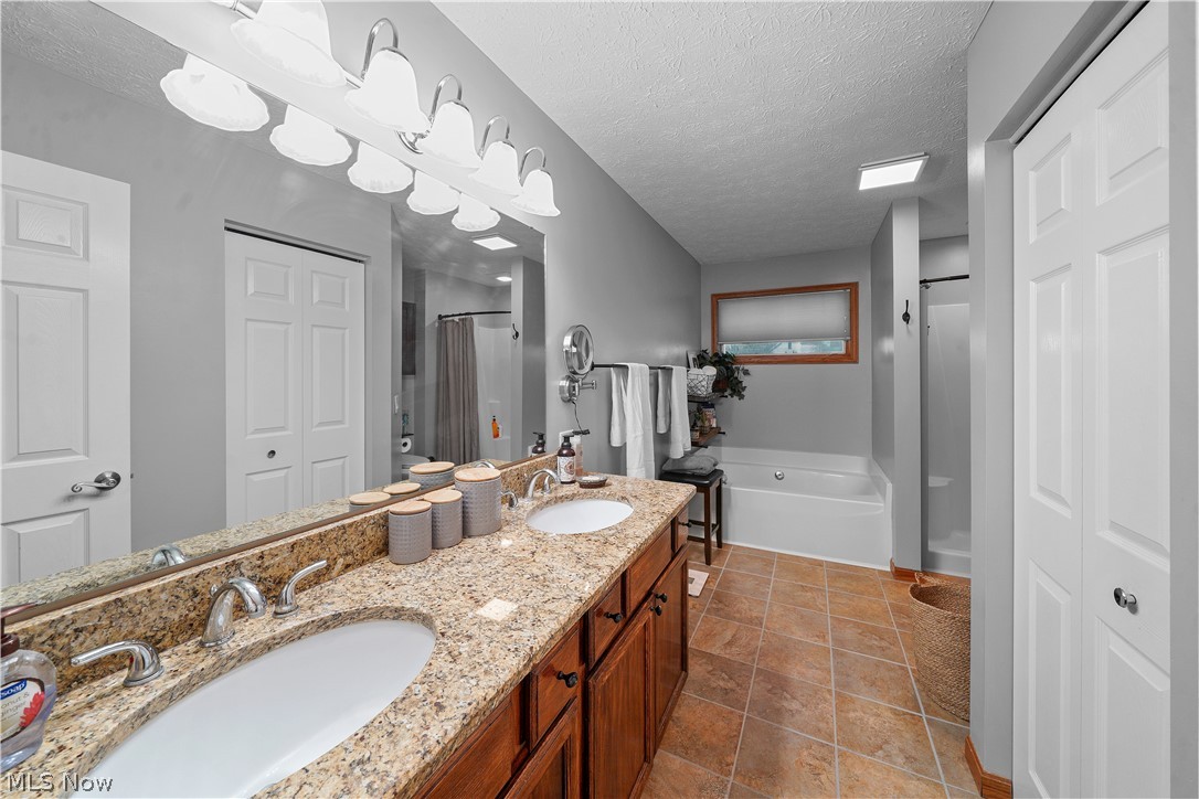 4849 Edson Road Kent, OH 44240 - Photo 21 of 50 Bathroom featuring tile flooring, a bathtub, dual bowl vanity, and a textured ceiling