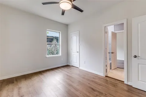 an empty room with wooden floor fan and windows