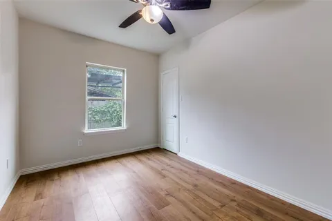 an empty room with wooden floor chandelier fan and windows