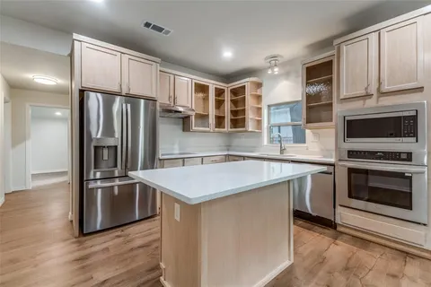 a kitchen with stainless steel appliances granite countertop a refrigerator a stove and a sink with wooden floor