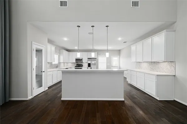 a kitchen with kitchen island white cabinets and stainless steel appliances