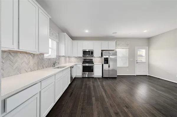 a kitchen with cabinets wooden floor and stainless steel appliances