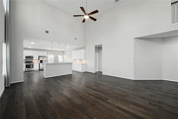 a view of empty room with wooden floor and kitchen view