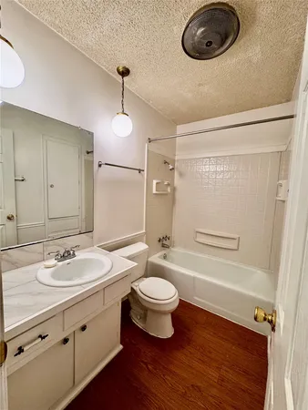 a bathroom with a granite countertop sink a toilet a mirror and bathtub
