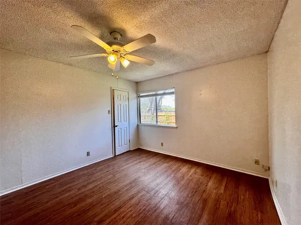 a view of an empty room with window and wooden floor