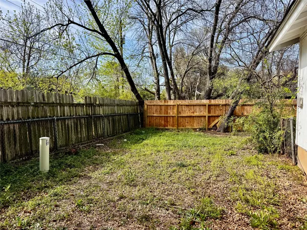 a view of backyard with wooden fence and a large tree
