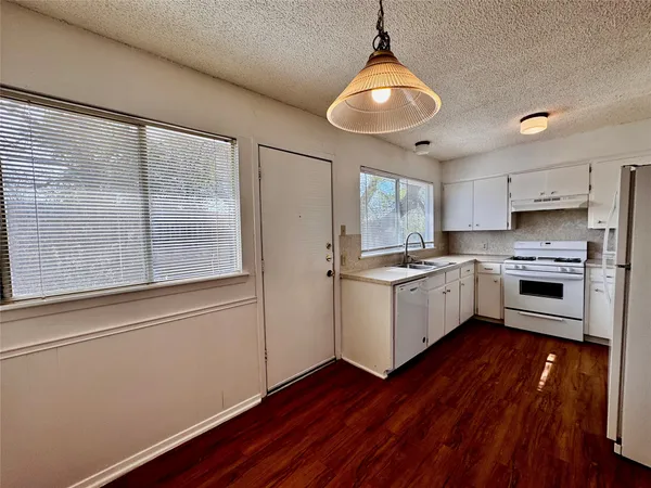 a kitchen with a refrigerator wooden floor and white cabinets