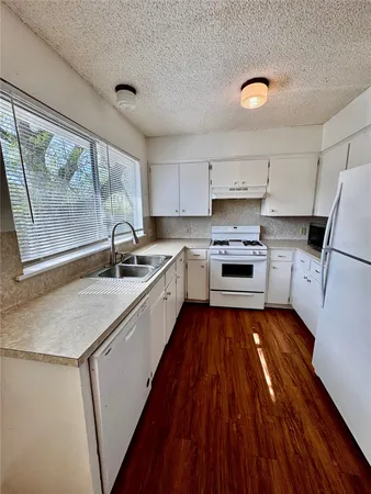 a kitchen with wooden floors a sink and appliances