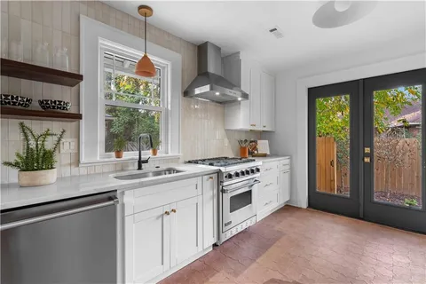 a kitchen with stainless steel appliances granite countertop a sink a stove and a wooden floors