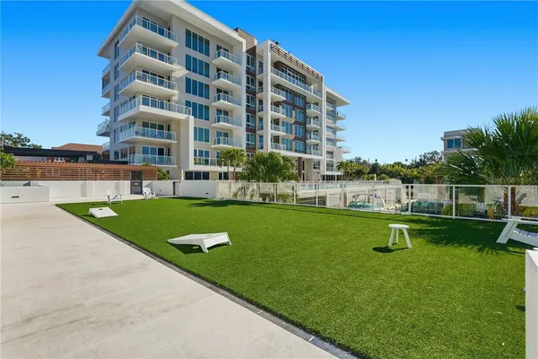 a view of a large pool with lawn chairs and large trees