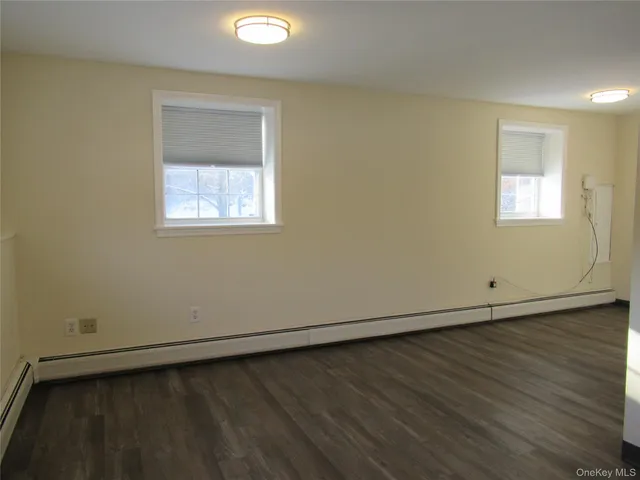an empty room with wooden floor & windows