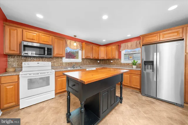 a kitchen with stainless steel appliances granite countertop a refrigerator a stove top oven a sink and dishwasher