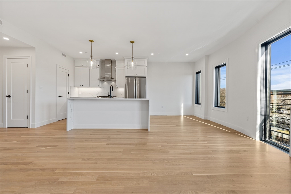 a view of a kitchen with kitchen island a sink wooden floor and a refrigerator