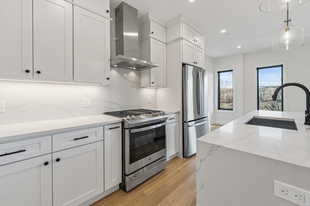 268 Bremen Street, Unit 2 Boston, MA 02128 - Photo 6 of 8 a kitchen with stainless steel appliances granite countertop a sink stove and refrigerator