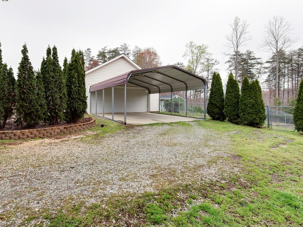 8124 Shoeline Road Stokesdale, NC 27357 - Photo 19 of 29 The carport sits just outside the garage with its own concrete pad.
