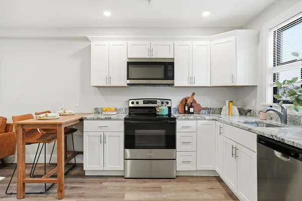a kitchen with stainless steel appliances granite countertop a stove a sink and a microwave