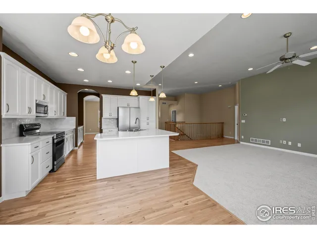 a large kitchen with kitchen island a stove a sink a center island and wooden floor