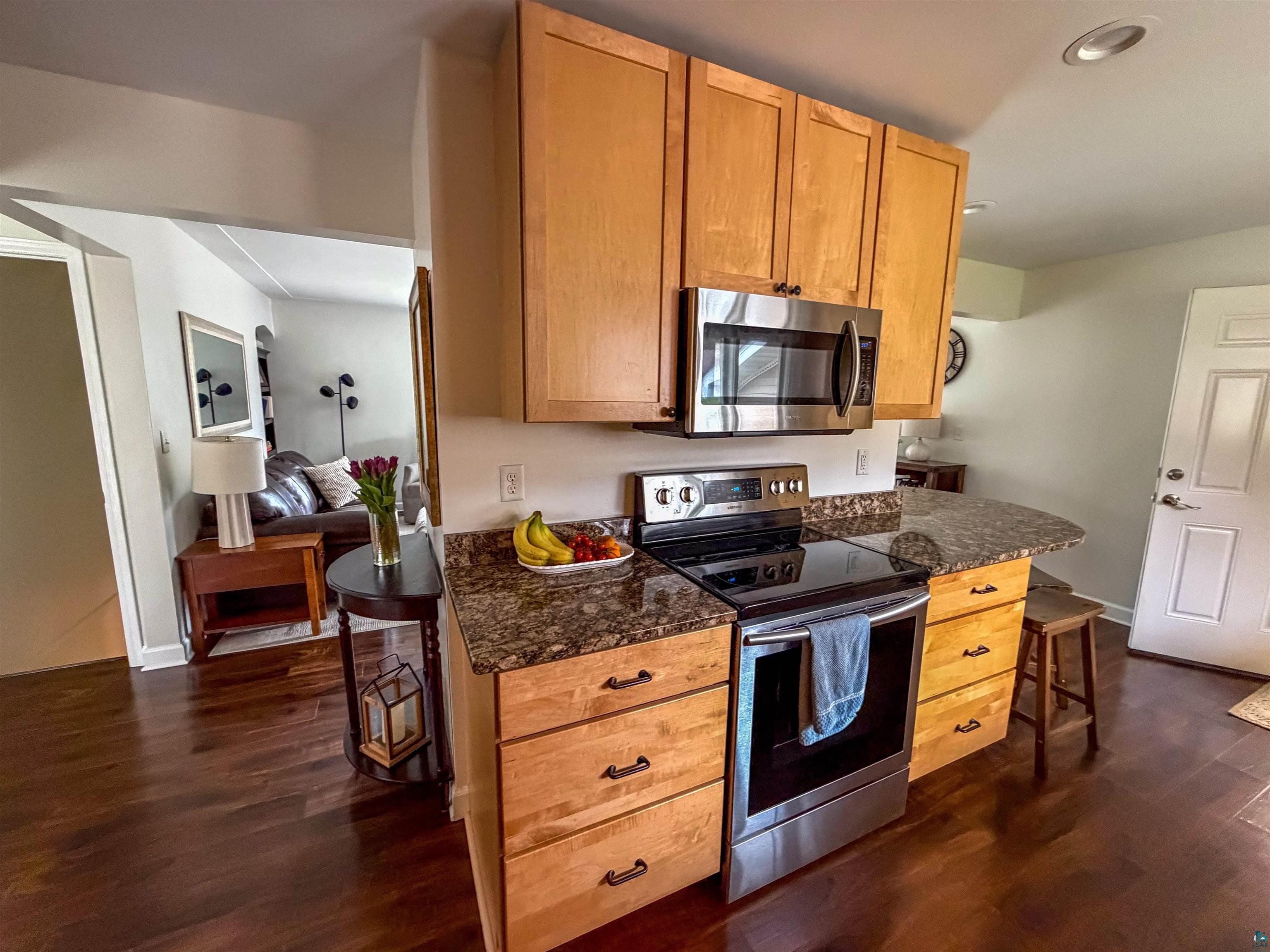3704 Greysolon Road Duluth, MN 55804 - Photo 6 of 51 Kitchen featuring wood-finish flooring, light wood cabinetry, stainless steel appliances, and a curved countertop with seating space