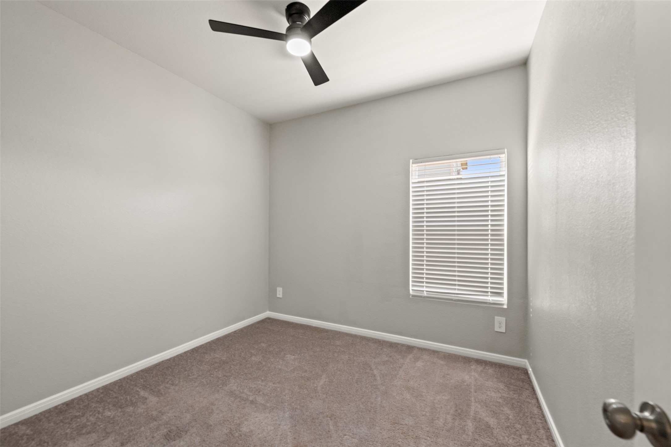 Comfortable bedroom featuring neutral finishes, carpet flooring, ceiling fan, and natural light.