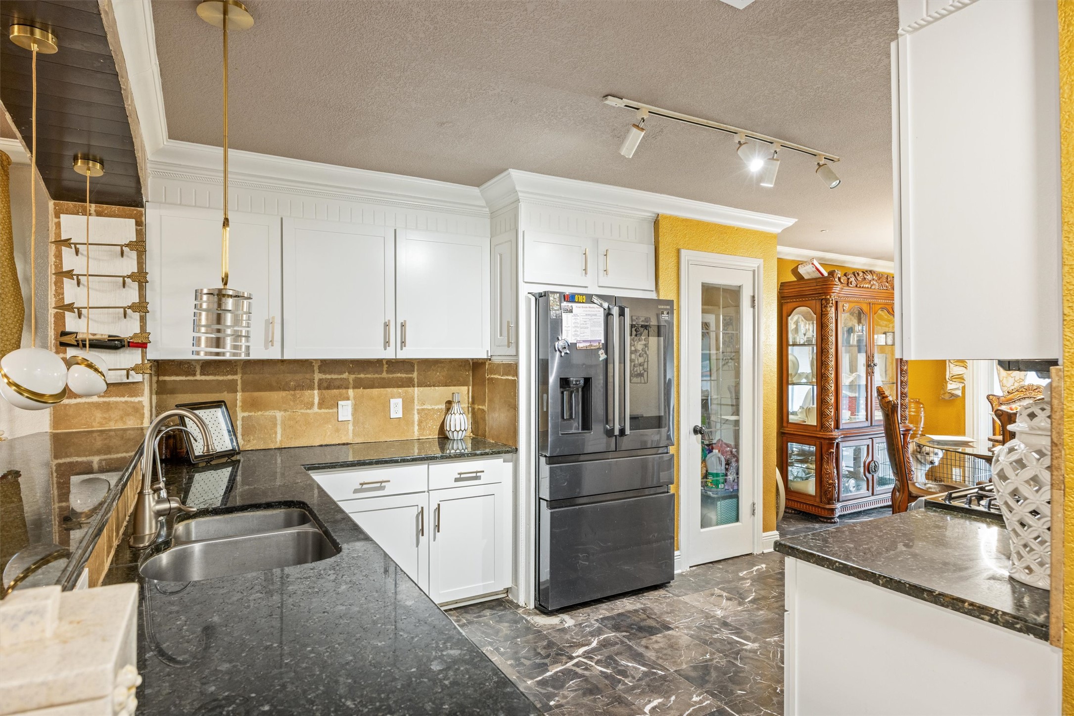 14409 Sandifer Street Austin, TX 78725 - Photo 11 of 31 Kitchen with crown molding, high end refrigerator, white cabinets, dark stone countertops, and a textured ceiling