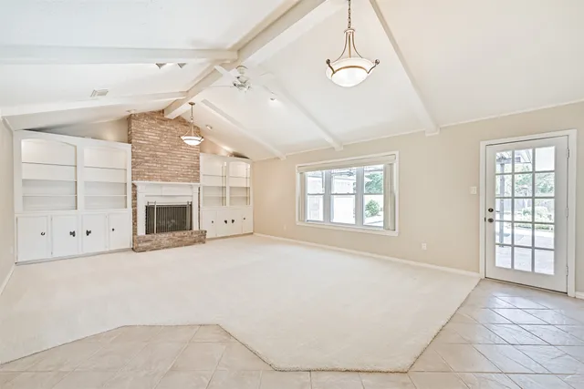a view of an empty room with a fireplace and a window