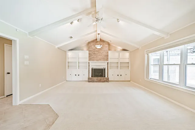 an empty room with windows and fireplace