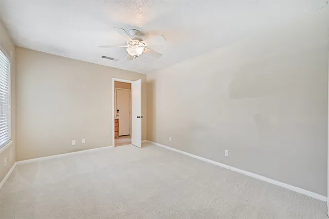 an empty room with a chandelier fan and windows
