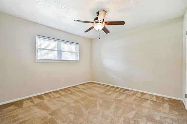 a view of a big room with a ceiling fan and window