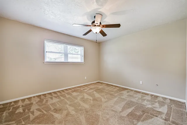 an empty room with windows and fan