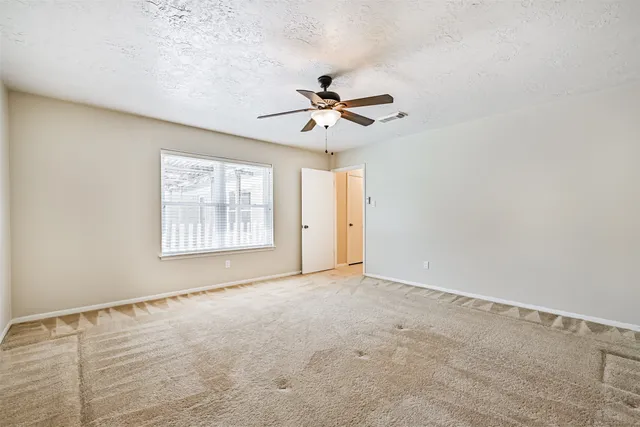an empty room with windows and fan