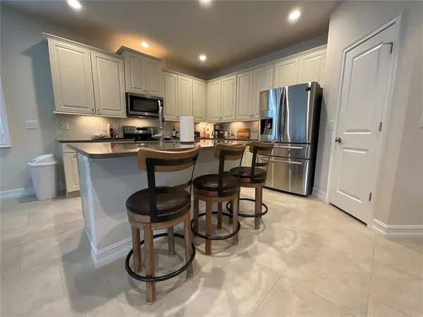 a kitchen with stainless steel appliances granite countertop a refrigerator a stove a sink dishwasher a dining table and chairs with wooden floor