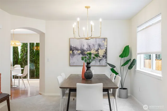 a dining room with wooden floor a chandelier a glass table and chairs