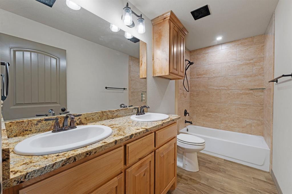 2387 County Road 407 Nemo, TX 76070 - Photo 11 of 30 a bathroom with a granite countertop sink a toilet a mirror and bathtub