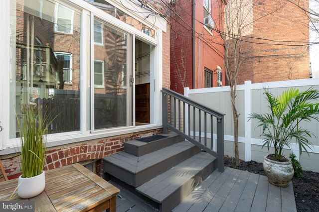 a view of a balcony with chairs potted plants and floor to ceiling window