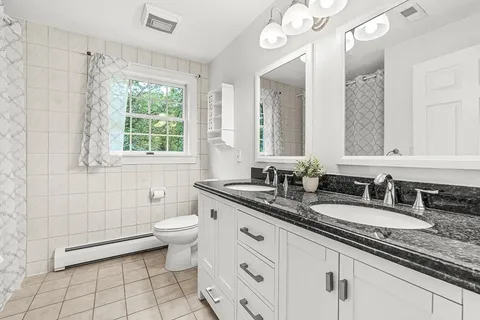 a bathroom with a granite countertop sink a toilet a mirror and a shower