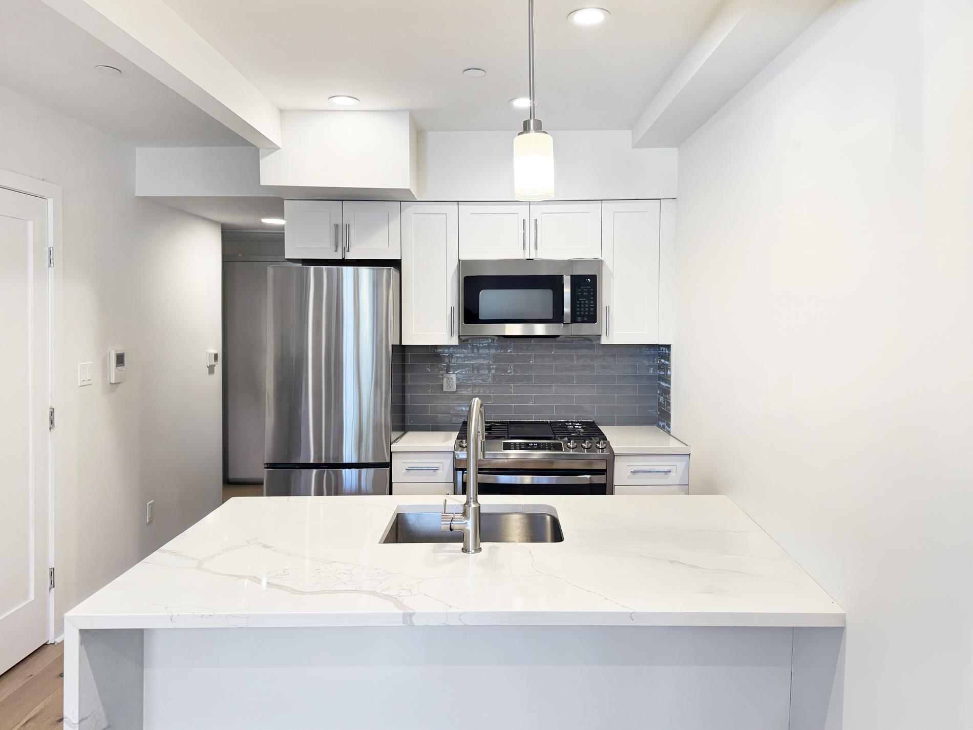 31-22 29th Street, Unit 2B Queens, NY 11106 - Photo 3 of 11 a kitchen with kitchen island a counter top a stove a refrigerator and a sink