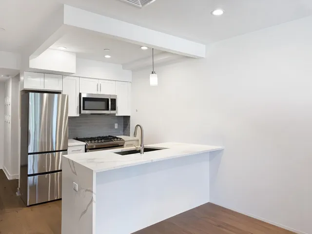 a kitchen with kitchen island a counter top a stove a refrigerator and a sink