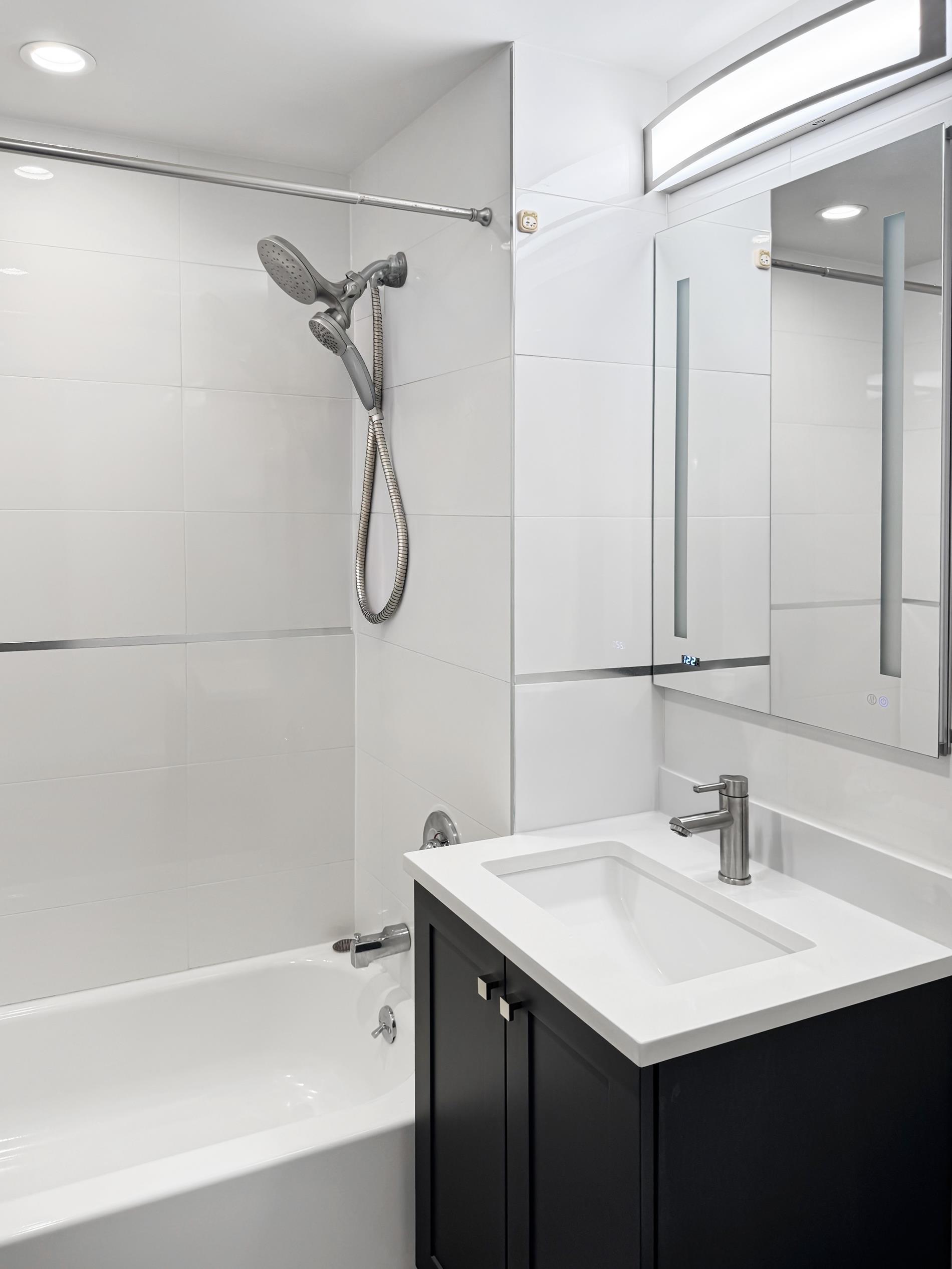 31-22 29th Street, Unit 2B Queens, NY 11106 - Photo 5 of 11 a bathroom with a sink a mirror and a bathtub