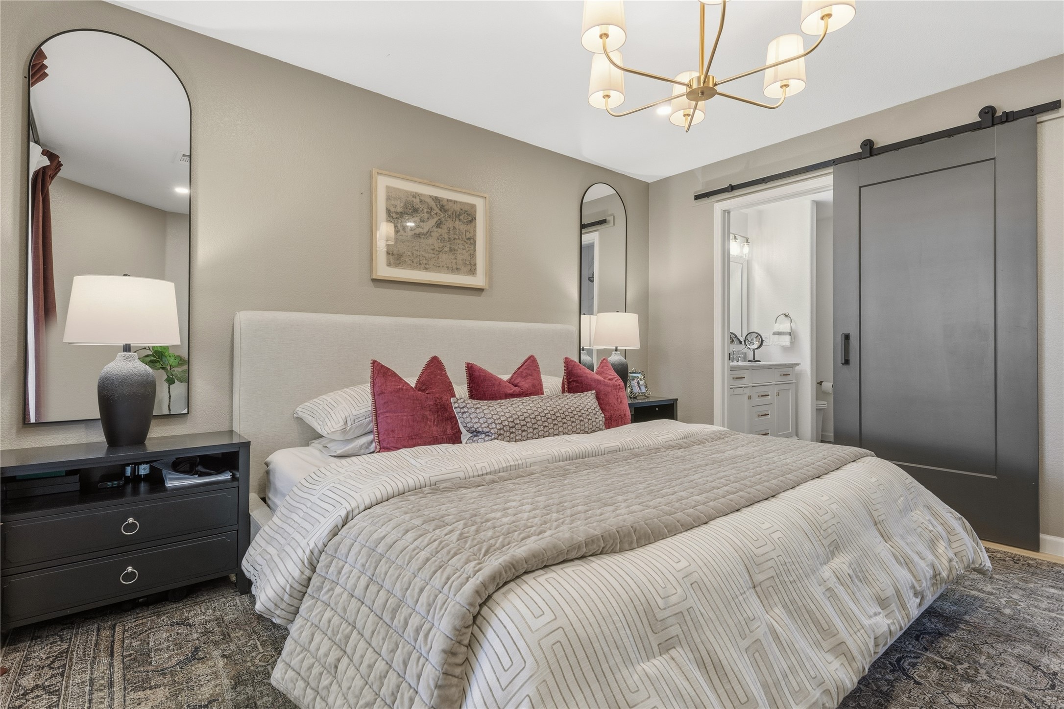 7400 South Glenn Street Austin, TX 78744 - Photo 14 of 36 Bedroom featuring a barn door, a chandelier, and ensuite bath