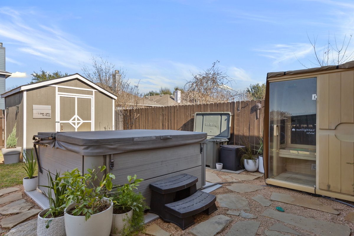 7400 South Glenn Street Austin, TX 78744 - Photo 25 of 36 Fenced backyard with a storage unit, a patio, and a hot tub