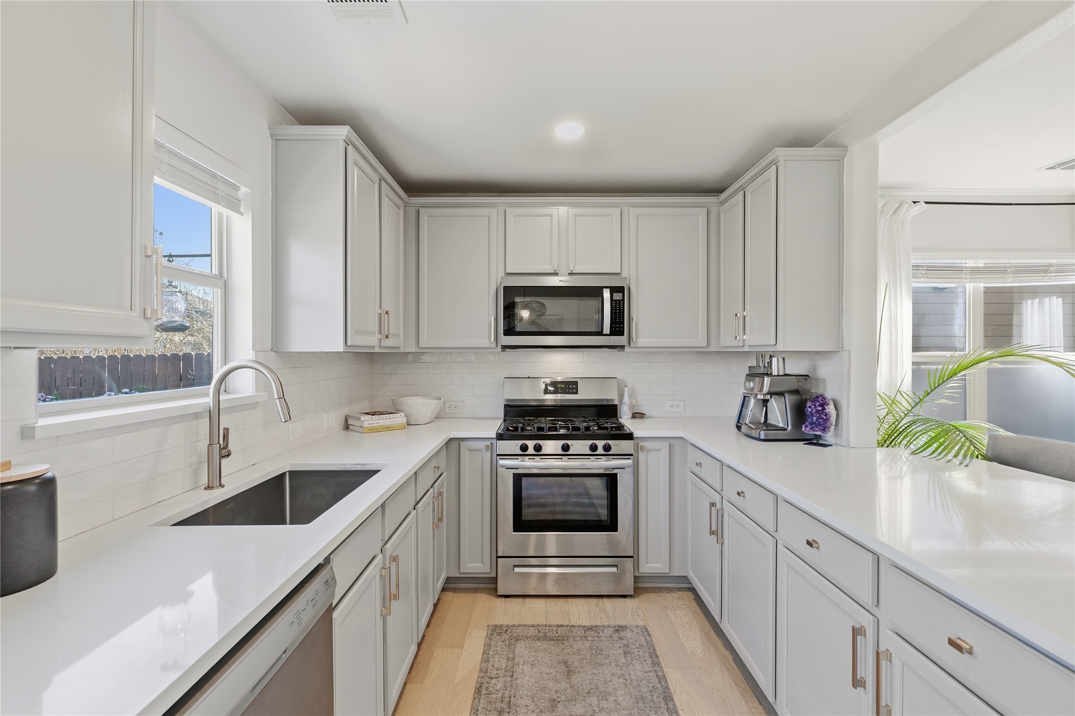 7400 South Glenn Street Austin, TX 78744 - Photo 6 of 36 Kitchen featuring stainless steel appliances, light wood-style floors, white cabinetry, recessed lighting, and tasteful backsplash