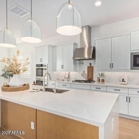 a kitchen with stainless steel appliances a sink a stove a dining table and chairs