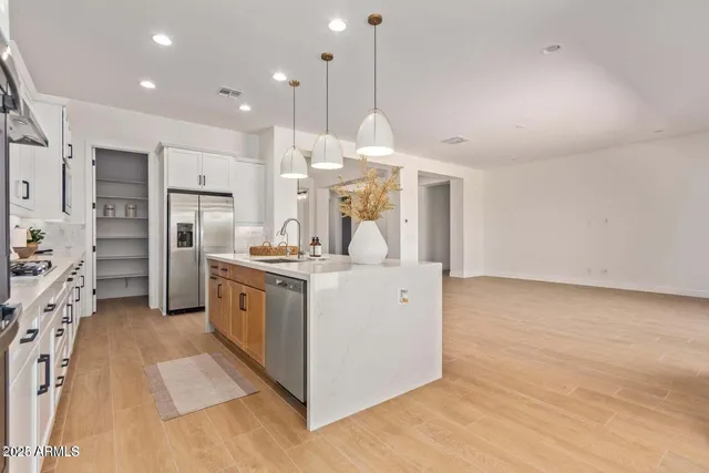 a kitchen with stainless steel appliances granite countertop a sink a stove and a wooden floors