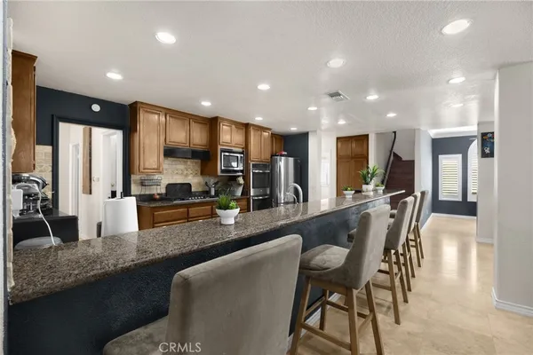 a large kitchen with a large counter top a sink stainless steel appliances and cabinets