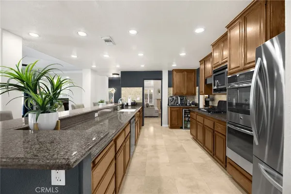 a kitchen with stainless steel appliances granite countertop a refrigerator a stove a sink and a microwave