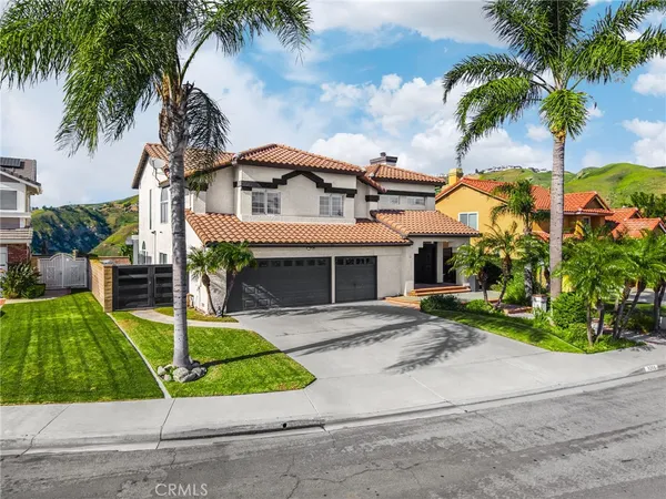 a front view of a house with a garden and palm trees
