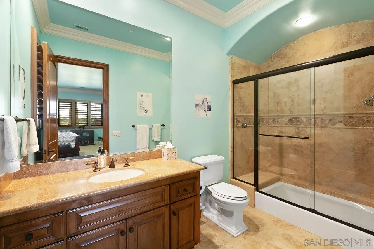 6658 Niemann Ranch Road Rancho Santa Fe, CA 92067 - Photo 28 of 35 a bathroom with a toilet a sink and glass door