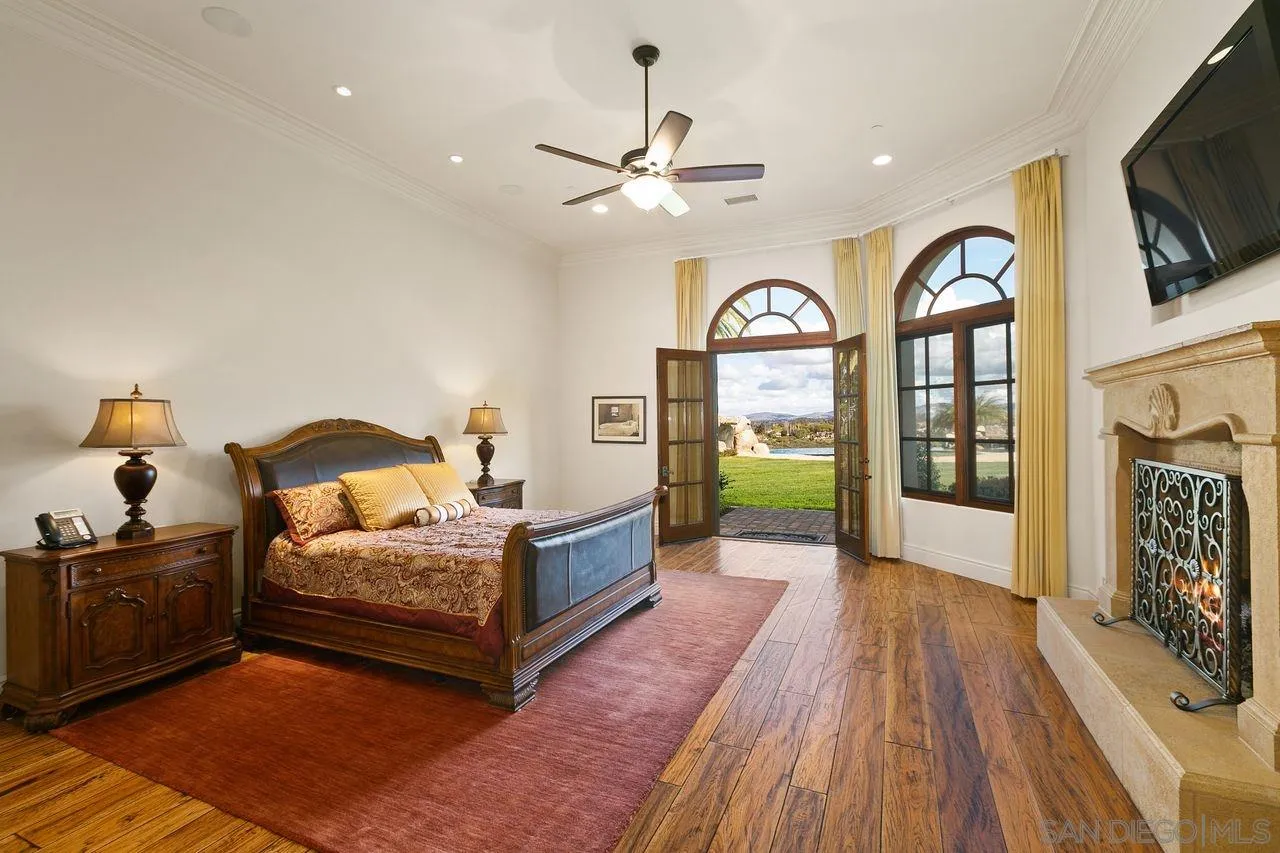 6658 Niemann Ranch Road Rancho Santa Fe, CA 92067 - Photo 5 of 35 a bedroom with a bed a mirror on dresser and a chandelier