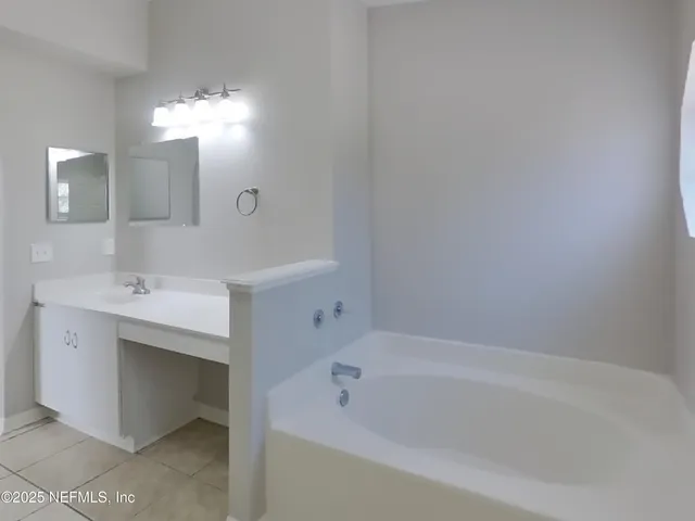 a bathroom with a bathtub a mirror a sink and vanity