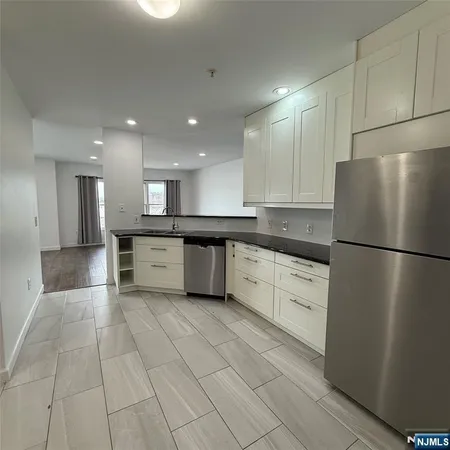 a kitchen with a refrigerator a stove top oven and white cabinets